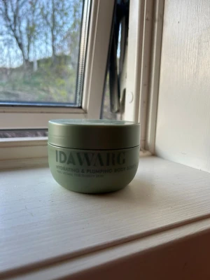 Ida Warg Hydrating Body Soufflé - Grön rund burk med Ida Warg Hydrating & Plumping Body Soufflé. Krämen är vit och har en lätt, fluffig konsistens. För dig som vill ha återfuktad och spänstig hud. Snygg minimalistisk design och praktisk skruvlock. Luktar as gott. 