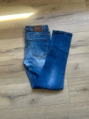Blå jeans från Dsquared2 - Snygga blå jeans från Dsquared2 med klassisk femficksdesign och läderpatch bak i midjan. Jeansen har en något smalare passform och är tillverkade i denim med lätt tvättad effekt. Perfekta för en trendig och avslappnad stil.