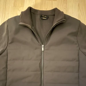 Mörkgrå Massimo Dutti cardigan - En stilren cardigan från massimo dutti i väldigt bra skick, knappt använd. Storlek L/M. Stickad rygg och ärmar med en framsida i mer av ett jacka material med dun fyllning. En perfekt jacka till våren och kommande sommarkvällar. Nypris ca 1200kr.