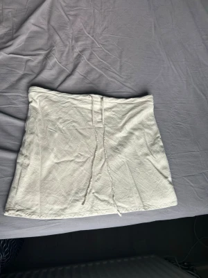 Linnekjol med snörning - Säljer en supersöt linnekjol med snörning framtill. Kjolen har en enkel och clean design med rak passform och är tillverkad i ett mjukt linnetyg som känns bekvämt. Perfekt att matcha med en crop top eller hoodie för en chill look. Säljer då den tyvärr inte passar längre. Köpt på hm i Spanien.