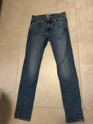 Blå slim fit jeans - Säljer ett par klassiska blå slim fit jeans med fem fickor och normal midja. Jeansen har en snygg tvätt och raka ben. Perfekta till sneakers eller boots och passar till många olika stilar. Storlek 29/32