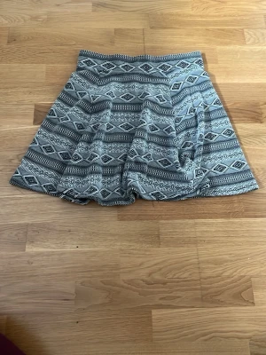 Svartvita mönstrad kjol - Snygga svartvit kjol med grafiskt mönster. Kjol med dragkedja bak. Perfekta för dig som vill ha både stil och komfort. Materialet känns mjukt och lätt, passar till många olika looks.