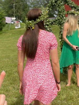 Röd blommig klänning midsommar - Söt röd klänning med röd / vitt blommönster och v-ringning. Fint skick. Storlek Small. Köpt på Chiquelle.
