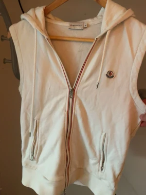 Vit Moncler väst med huva och dragkedja - Säljer min moncler hooded vest eftersom den är för liten, köpt på kaspersheat finns kvitto, ganska liten i storlek S/XS