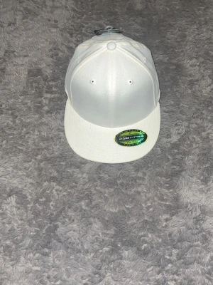 Vit Flexfit-keps ART 19 - En stilren, helvit keps av märket "210 Fitted". Kepsen har rak skärm och är i nyskick med originaletiketterna kvar.