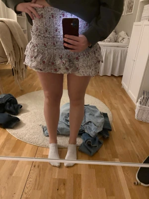 Kjol från Neo Noir - Supersöt kort kjol i vitt med blommigt mönster i rött och rosa. Från Neo Noir, super bra skick