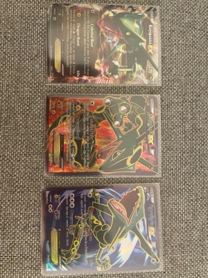 Rayquaza EX Pokémonkort 3 st - Säljer ett 3-pack Rayquaza EX Pokémonkort med olika motiv. Korten har färgstarka illustrationer i grönt, svart, rött och guld, och är i plastfickor. Perfekt för samlare eller dig som vill boosta din kortlek med legendariska Rayquaza.