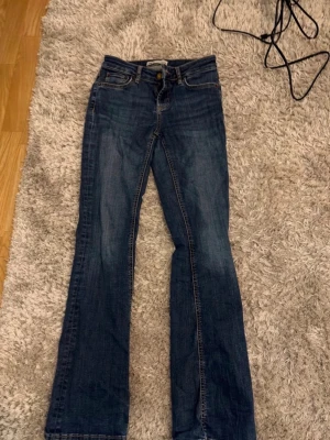 Mörkblå bootcut jeans - Snygga mörkblå bootcut jeans med klassiska fem fickor och kontrastsömmar. Jeansen har en lätt tvättad look och normal midja. Perfekta för dig som gillar en avslappnad men ändå trendig stil.