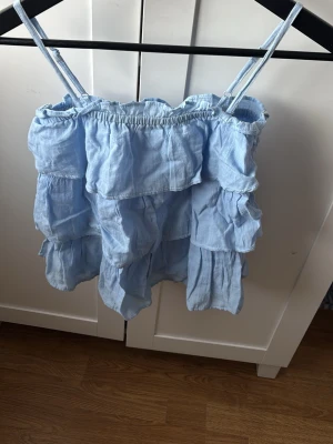 Ljusblå volangig linnetopp - Supersöt ljusblå linnetopp med tunna axelband och flera lager volanger. Toppen har en luftig och flowy känsla, perfekt för varma dagar. Elastisk upptill för skön passform och justerbara axelband. Passar perfekt till jeans eller kjol. Priset kan diskuteras 💞