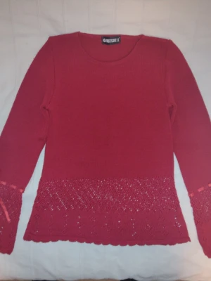 Röd finstickad Y2K  tröja med "spets" från Nutshell - Supersnygg röd finstickad y2k tröja från Nutshell i en långärmad modell. Tröjan har fina spetsliknande detaljer - ett hålmönster nedtill samt på ärmarna - och ett litet "sidenband" knutet vid ärmsluten. Storlek S/M, men jag skulle säga att den är mer som XS/S.