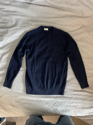 Mörkblå tröja John Henric - Snygg mörkblå Kashmir tröja från John Henric med rund halsringning och ribbade muddar vid ärmslut och nederkant. Sitter som S. Perfekt basplagg i garderoben, enkel att matcha och skön att bära. Klassisk och stilren design. Passa på att köpa fler plagg/accessoarer samtidigt så får du en bundle rabatt!