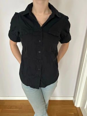 Svart kortärmad skjorta - Svart kortärmad skjorta med knappar framtill. Skjortan har två bröstfickor och klassisk krage. Perfekt till vardags och till fest. 🎉💖