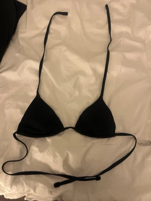 Svart trekantsbikini med knyt calzedonia - En stilren svart trekantsbikini med tunna band som knyts i nacken och runt ryggen. Klassisk modell som passar perfekt till stranden eller poolen. Materialet känns mjukt och följsamt mot huden.