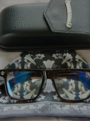 Chrome Hearts | Blue light glasses - Snygga solglasögon från CH med svartbrun båge i klassisk rektangulär form. De har flera små silverdetaljer vid sidan som är ikoniska för märker . Kommer med ett svart fodral i konstläder och en mönstrad putsduk.