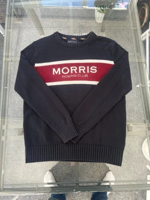 Morris Rowing Club stickad tröja – Navy – Strl L - Säljer en sjukt clean stickad tröja från Morris R. Club. Marinblå med röd/vit panel och stor broderad MORRIS ROWING CLUB logga framtill. Riktig preppy / old money vibe 🔥  Perfekt till jeans, chinos eller över skjorta. Funkar både casual och mer uppstyrt.  • Storlek: L • Färg: Navy (mörkblå) med röd/vit detalj • Skick: Väldigt fint skick, inga hål eller fläckar • Passform: Regular fit • Material: Mjuk bomullsstickad  Riktigt snygg statement knit som ger den där klassiska skandinaviska stilen.  