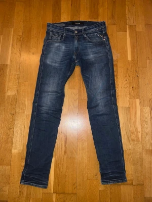 Mörkblå slim fit jeans från Replay - Snygga mörkblå slim fit jeans från Replay med slitningar och kontrastsömmar. Klassisk femficksmodell med läderpatch bak i midjan och diskret tvättad look. Perfekta för en trendig och avslappnad stil.