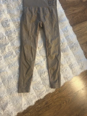 Grå seamless leggings  - Säljer ett par grå seamless leggings  med hög midja och scrunch-detalj bak. Stretchigt material som sitter tight och formar sig efter kroppen. Diskret logga vid linningen. Perfekta för gymmet eller chill dagar. Använd 1 gång