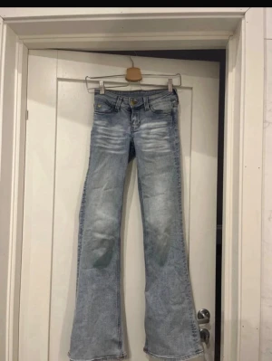 Ljusblå bootcut jeans från Cheap Monday - Säljer ett par ljusblå bootcut jeans från Cheap Monday med slitna detaljer och klassisk femficksmodell. Jeansen har en snygg tvätt och vida ben som ger en retrovibe. Perfekta för dig som gillar en avslappnad men trendig stil.