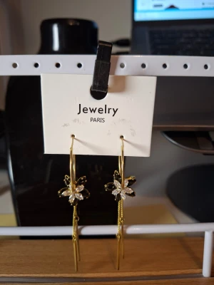 Guldiga örhängen med blomdetalj - Överge samlingen, utförsäljning till låga priser