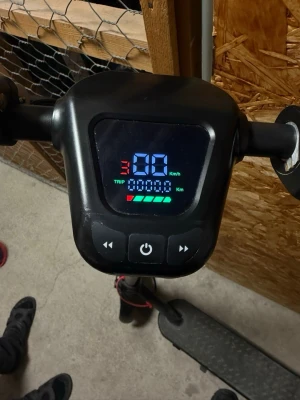Svart elscooter med digital display - Säljer en svart elscooter med tydlig digital display som visar hastighet, batterinivå och körsträcka. Scootern har röda detaljer på kablarna och robusta hjul. Perfekt för smidig transport i stan eller till skolan.