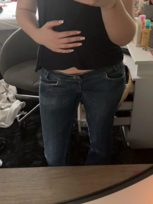 Mörkblå bootcut jeans - Snygga mörkblå bootcut jeans med klassisk femficksdesign och låg midja. Jeansen har en lätt tvättad look och raka ben som blir lite vidare nedtill. Perfekta för en avslappnad och trendig stil.
