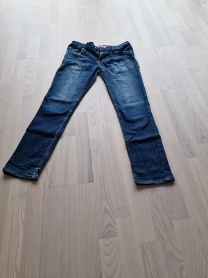 Mörkblå raka jeans från Levi's  - Snygga mörkblå jeans med raka ben och klassisk femficksdesign. Jeansen har en lätt tvättad look framtill och bakfickor. Perfekta för en avslappnad och trendig stil. Storlek 176 men sitter som W28 ungefär.