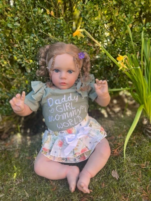 🌼Söt Reborn🌼 - Söt docka med brunt lockigt hår i flätor och en lila blomma i håret. Dockan har en grön topp med texten 'Daddy's Girl Mommy's World' och puffärmar samt en vit kjol med blommönster och rosett. Perfekt för lek eller dekoration. Inga skavanker och mjuk kropp för en realistisk känsla. Kontakta för att diskutera pris eller för mer bilder . Ny pris 900kr 