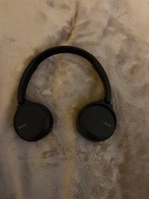 Svarta on-ear hörlurar från Sony - Snygga svarta on-ear hörlurar från Sony med stilren design. Hörlurarna har vadderade kåpor och justerbart huvudband i plast och konstläder för skön passform. Perfekta för musik, gaming eller videos.