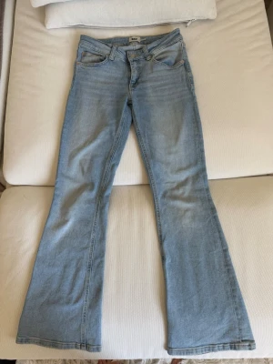 Ljusblå bootcut jeans från Lager 157 - Säljer ett par ljusblå bootcut jeans från Lager 157 med klassisk femficksmodell och normal midja. Jeansen har utsvängda ben och är tillverkade i mjukt denimtyg med en snygg tvätt. Perfekta för en avslappnad och trendig look.