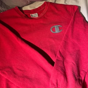 Röd sweatshirt från Champion - Cool röd sweatshirt från Champion med broderad logga på bröstet. Tröjan har rund halsringning och långa ärmar. Perfekt för en avslappnad och sportig stil. Materialet känns mjukt och bekvämt mot huden.