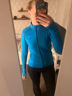 Träningströja med zip up playteck by name it  - Jättefin träningströja i en blå fin färg från playteck by name it.  Storlek 158-164, väldigt skönt och stretchigt material.  Reflex längst upp på ryggen samt i en liten logga på bröstkorgen som gör att man syns extra bra i mörker.   Köp gärna via bundle för att få rabatterade priser!