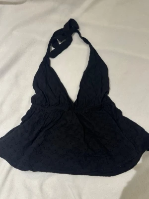 Svart halterneck linnetopp - Svart halterneck linnetopp med knytning i nacken och broderade detaljer. Toppen har djup v-ringning och är ärmlös, perfekt för en trendig och avslappnad look. Lätt och luftig modell som passar till många olika outfits. Byxor i storlek xs topp storlek M men passade mig som oftast har xs-s