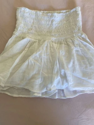Vit kort kjol med smock i midjan ifrån Nelly💓 - En vit kjol med smockad midja och luftig, lätt utsvängd passform. Den är från Nelly i storlek xxs💓
