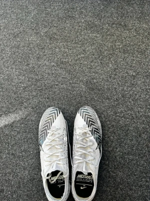 Nike vita fotbollsskor med zigzag-mönster - Pris går att diskutera…..Använda fåtal gånger. Kommer med väska till den som är helt ny inprincip…..         Snygga vita fotbollsskor från Nike med svart zigzag-mönster.