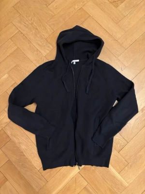 Stickad zip hoodie - En mörkblå stickad hoodie från Paul Taylor med dragkedja framtill och två fickor. Modellen har huva med dragsko och långa ärmar. Perfekt för en avslappnad och stilren look. Materialet känns mjukt och bekvämt mot huden.