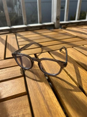 Glasögon som skyddar mot blått ljus - Snygga solglasögon med transparent grå båge och rektangulära linser. Perfekt för dig som vill ha en stilren och modern look. Bågen är gjord i syntetmaterial och har en klassisk form som passar de flesta ansikten. (UTAN STYRKA)