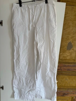Vita linnebyxor med dragsko - Snygga och luftiga vita linnebyxor med rak passform och elastisk midja med dragsko. Perfekta för en avslappnad och stilren look. Byxorna har fickor i sidorna och är tillverkade i 100% linne för maximal komfort.