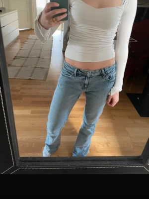 Vit långärmad topp - Säljer en vit, croppad topp med lång ärm och snygg v-ringad urringning. Toppen har en figurnära passform och är tillverkad i mjukt stretchigt material. Perfekt att styla med jeans eller kjol för en trendig look.