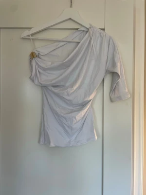 Vit oneshoulder topp från Zara - Säljer en så fin onesoulder topp från Zara🩷🩷toppen har guld detaljer och är så fin!!💞strl S!!