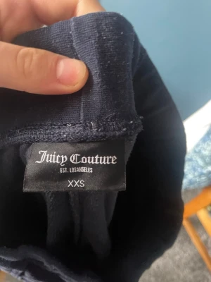 Mörkblå velourbyxor Juicy Couture - Säljer ett par mörkblå mjukisbyxor från Juicy Couture i velour. Byxorna har raka ben, bred resår i midjan och stora fickor framtill. Perfekta för en chill och avslappnad stil.
