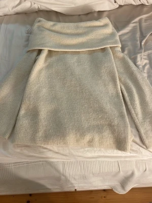 Vit ribbstickad offshoulder - Säljer en vit ribbstickad offshoulder tröja med långa ärmar. Tröjan har en avslappnad passform. Materialet känns mjukt och mysigt, perfekt för kyliga dagar.