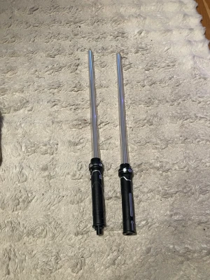 Dubbel ljussabel för cosplay - Säljer en dubbel ljussabel med svart handtag och genomskinliga blad, perfekt för Star Wars-inspirerad cosplay eller maskerad. Handtagen kan användas separat eller sättas ihop till en lång stav. Tillverkad i plast med detaljer i silver.