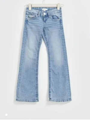 Ljusblå bootcut jeans med fickdetaljer -  Ljusblå jeans från Gina Tricot med bootcut passform och klassiska fem fickor. Jeansen har snygga fickdetaljer med knapp framtill och är tillverkade i mjukt denimtyg. Väl använda, men fortfarande i bra skick.