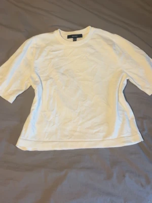 Vit basic t-shirt från vero Moda  - En enkel vit t-shirt från vero Moda med rund hals och korta ärmar. Tillverkad i mjuk bomull och har en normal passform som funkar till allt. Perfekt basplagg för garderoben.