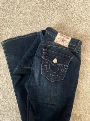 Mörkblå bootcut jeans True Religion - Snygga mörkblå bootcut jeans från True Religion, storlek w25. Slitage längst ner. Modellen BECCA med midrise och bootcut! 