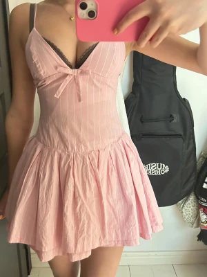 Zara rosa kort klänning med rosett - Söt rosa kortklänning med tunna axelband, v-ringning och liten rosett framtill. Klänningen har vita ränder.💕 använd ett fåtal gånger, säljs inte längre på Zara 