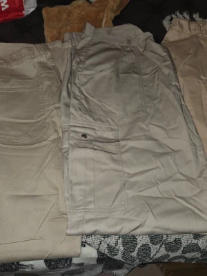 Beige cargobyxor med fickor - Snygga beige cargobyxor med flera praktiska fickor på sidorna och bak. Byxorna har en avslappnad passform och är tillverkade i ett mjukt bomullsmaterial. Perfekta för en casual och trendig stil.