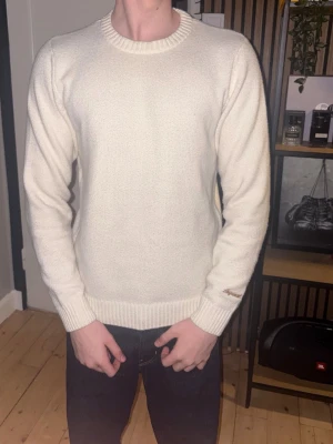 Vit stickad tröja Jack & Jones - Klassisk vit stickad tröja från Jack & Jones med rund halsringning och ribbade muddar vid ärmslut och nederkant. Enkel och stilren design som passar till det mesta. Perfekt för lager på lager och snygg till jeans.