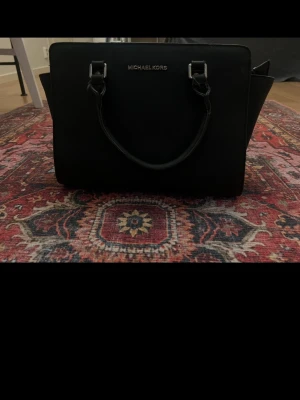 Svart handväska från Michael Kors - Säljer denna handväska, i använt skick, dragkedjan går ej att stänga. Man kan se defekter på den. Vet inte om den är riktig eller inte 
