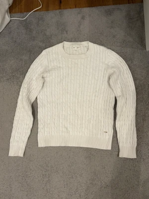 Vit stickad  - Kabelstickad vit tröja från Holly & Whyte by Lindex. Tröjan har rund halsringning, långa ärmar och ribbade muddar vid ärmslut och nederkant. Materialet känns mjukt och bekvämt, kliar inte alls. Tröjan är i storlek M men tycker den sitter lite mindre än hur M brukar sitta. 